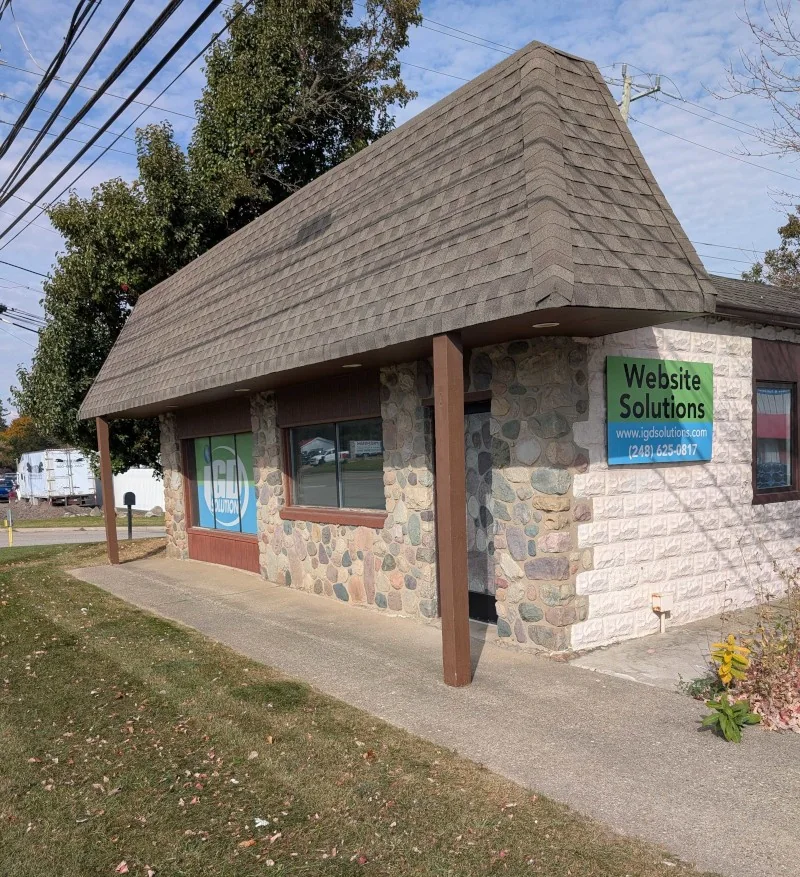 The IGD Solutions office at 9340 Dixie Hwy in Clarkston: a stone-fronted building under a shingled roof, with a Website Solutions sign by the door